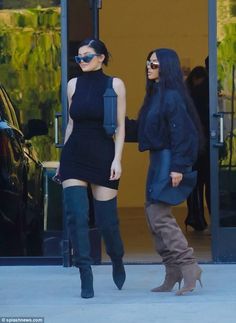 two women in black dresses and boots are walking together