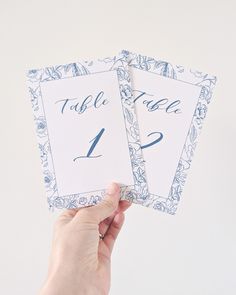 someone holding up two cards that say table 1 and 2