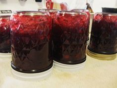 four jars filled with red liquid sitting on top of a counter next to each other