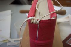 a close up of a red cylinder on a table with papers and scissors in the background