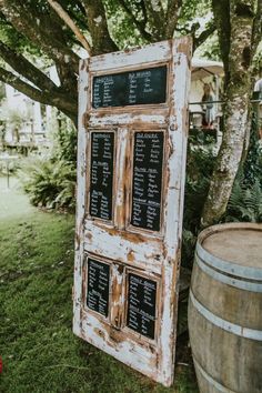 an old door is sitting in the grass next to a barrel with chalk writing on it