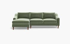 a green couch sitting on top of a white floor next to a wooden leg chair