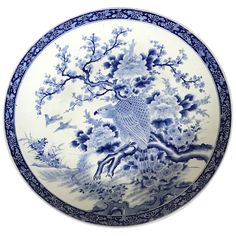 a blue and white plate with an image of a bird on the tree in it