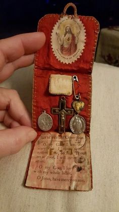 a hand holding an open red case with two silver crosses and other items in it