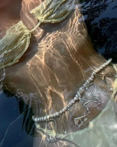 a woman's torso in the water with pearls on it