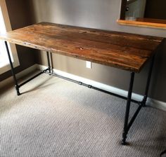 a wooden table sitting on top of a carpeted floor next to a window in a room