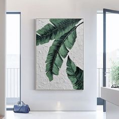 a large painting hanging on the wall in a white room with a blue handbag next to it