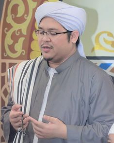 a man wearing a white turban and holding a cell phone in his hand