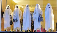 several white ghost costumes are displayed in a store window