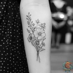 a black and white photo of a flower tattoo on the left arm, with flowers in it