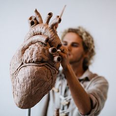 a man holding a fake human heart in front of his face and making it look like he's working on something