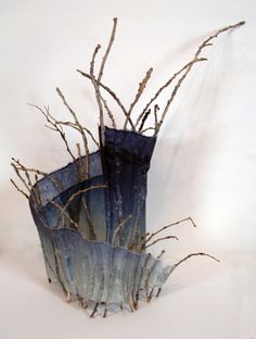 two blue vases with branches in them on a white tableclothed surface,