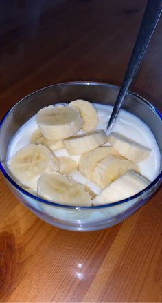 a bowl filled with yogurt and sliced bananas on top of a wooden table