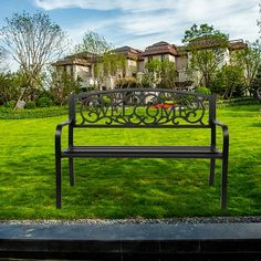 a metal bench sitting in the middle of a lush green park