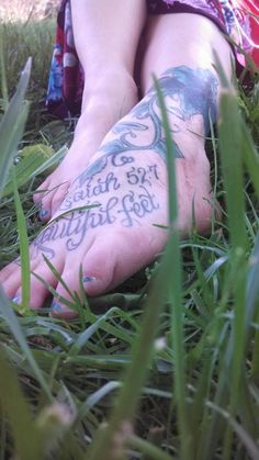 a person with tattoos on their feet sitting in the grass