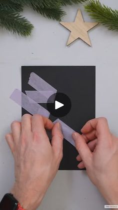 someone cutting out some paper with scissors on top of a piece of black and white paper