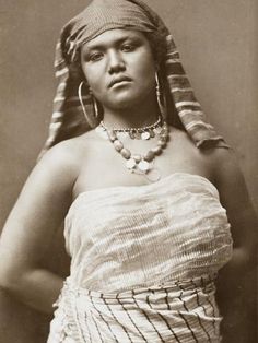 an old black and white photo of a woman wearing a headdress with her hands on her hips