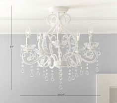 a white chandelier hanging from the ceiling in a room with gray walls and furniture