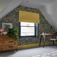 an attic bedroom with floral wallpaper and yellow roman shades on the window sill