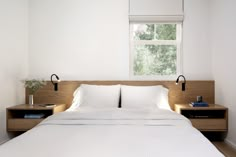 a bed with white sheets and pillows in a room