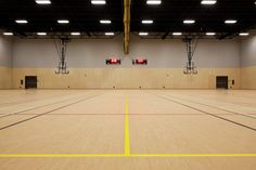 an empty basketball court with two red lights on each side and yellow lines in the middle