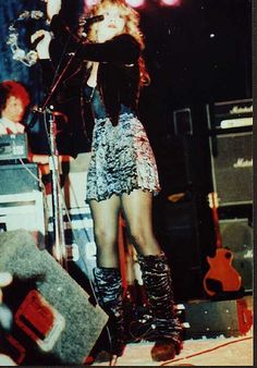 a woman standing on top of a stage next to a microphone and amps in front of her