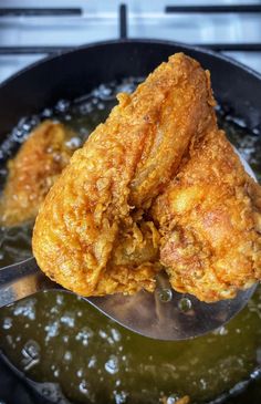 two fried chicken in a frying pan with a spoon