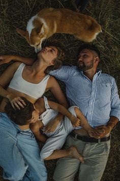 a man and woman laying on the ground with their two children next to an orange cat