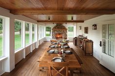 a long wooden table with plates and silverware on it in front of a fireplace