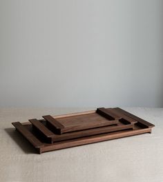 three wooden trays sitting on top of a white cloth covered tablecloth in front of a gray wall