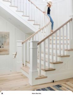 a woman is walking up the stairs in her house with a straw hat and jeans