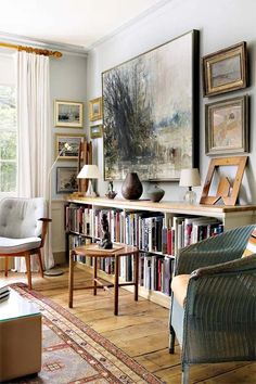 a living room filled with furniture and bookshelves next to a painting on the wall