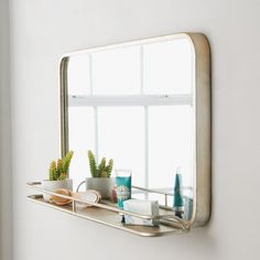 a mirror hanging on the side of a wall next to a shelf filled with items