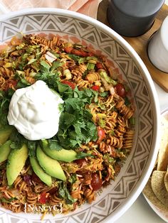 a white bowl filled with pasta salad and topped with sour cream