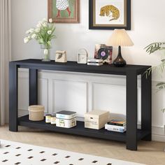 a black console table with books and pictures on the wall