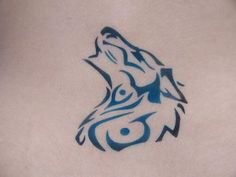 a tattoo on the back of a woman's stomach with a wolf head in blue ink