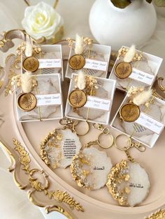 there are many keychains on the tray that have been decorated with gold and white flowers