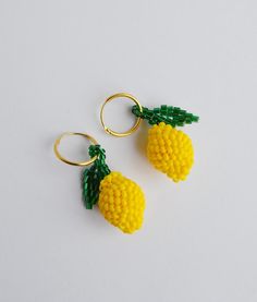 two yellow pineapples are hanging from gold hoop earrings on a white surface,