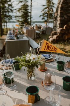 the table is set with wine glasses, plates and napkins for two people to eat