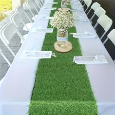 a long table with white chairs and green grass on the runner line is decorated with baby's breath flowers