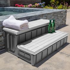 two white benches sitting next to a swimming pool