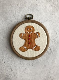 a wooden frame with a small embroidered ginger on it's side and a keychain hanging from the front