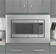 a stainless steel microwave oven sitting on top of a counter next to cabinets and drawers