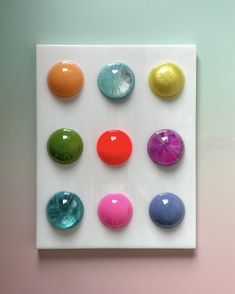 a square white plate with different colored balls on it's side and one in the middle