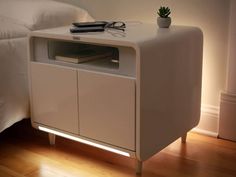 a white cabinet sitting on top of a wooden floor next to a neatly made bed