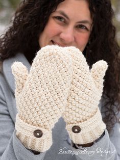 a woman is smiling while holding up her mitts