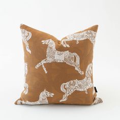 a brown pillow with white horses printed on the front and back, sitting on a white background