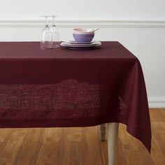 a table with a plate and bowl on it in front of a white wall next to a wooden floor