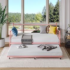 a pink metal daybed in front of a large window with lots of natural light