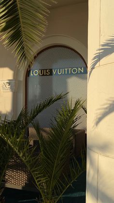 the entrance to louis vuitton is surrounded by greenery and palm tree leaves